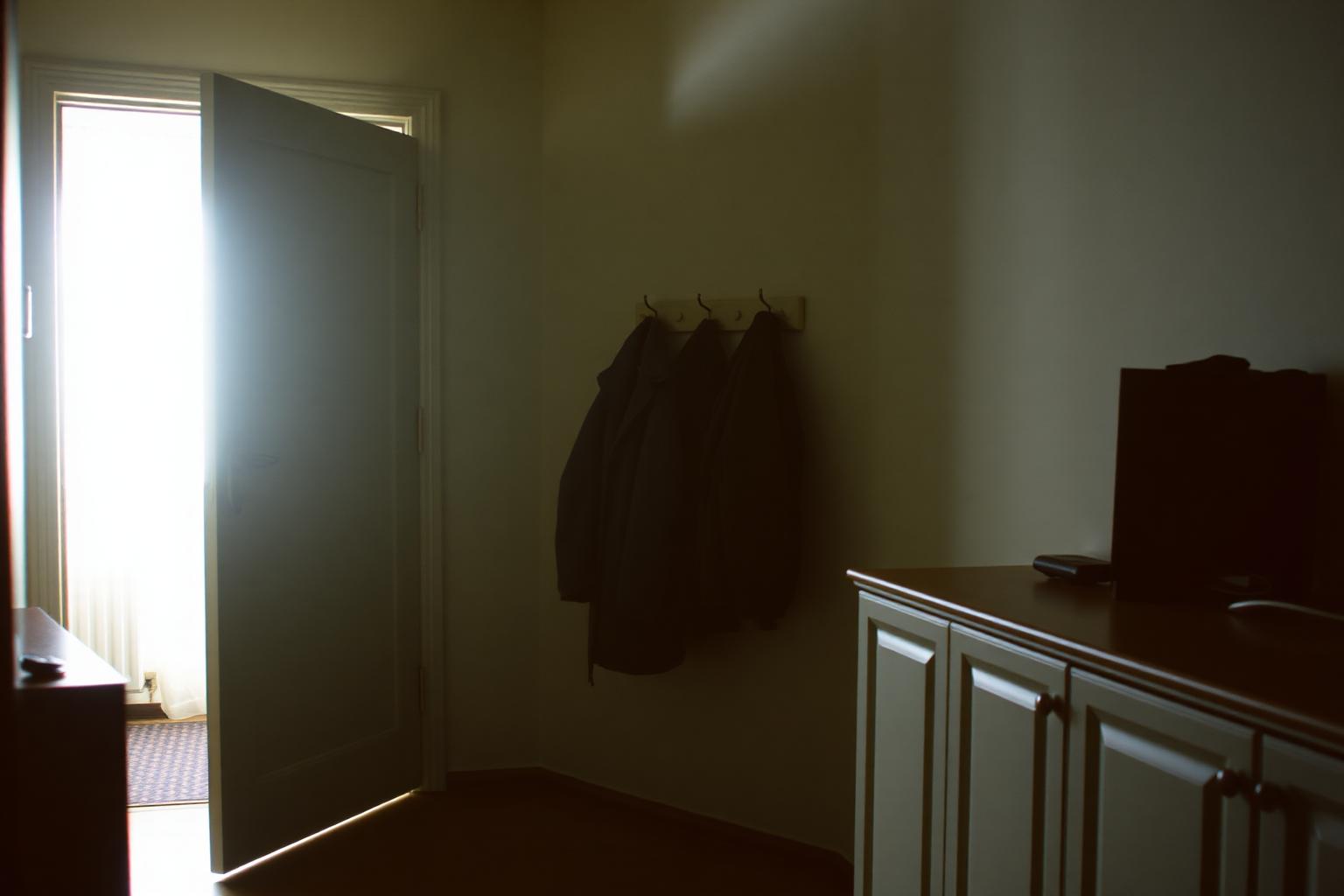 Wohnungsflur von innen im Gegenlicht, die Wohnungstür steht offen.